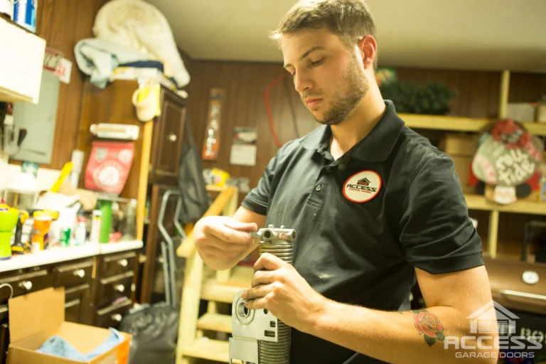 An Access Garage Doors technician inspects a garage door spring mechanism in a workshop